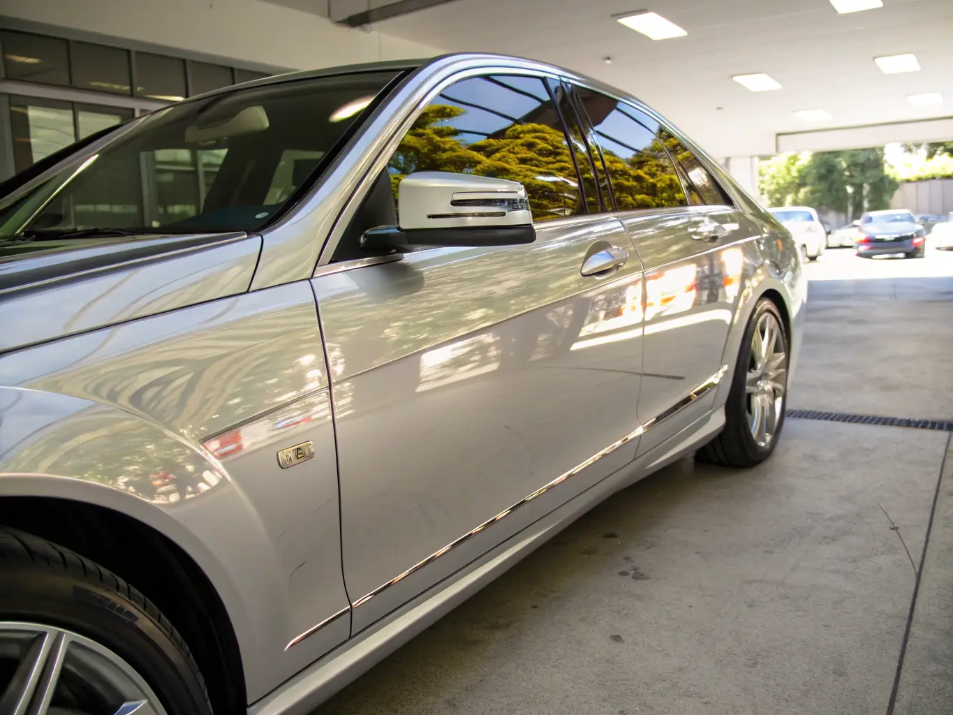 A shiny, freshly detailed car parked outdoors with a clean, reflective surface, showcasing the results of an exterior detailing service.